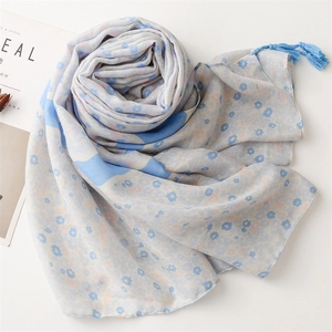 Detail showing blue floral pattern scarf with delicate fringes on woven fabric