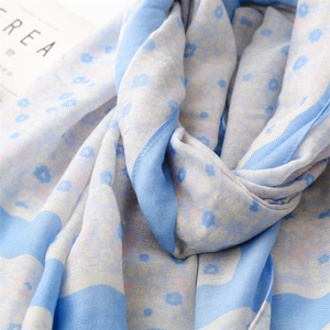 Close-up of light blue floral cotton linen scarf featuring soft fringe and twill texture