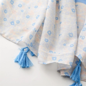Detail of light blue floral scarf featuring soft cotton-linen texture and elegant tassels