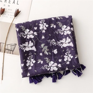 Detail of purple floral beach scarf with fringe trim on minimalist white background