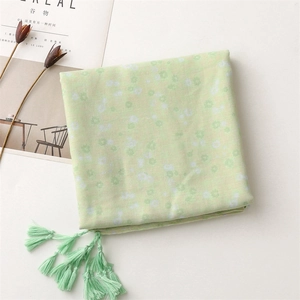 Detailed view of light green floral scarf with soft tassels and white flower pattern