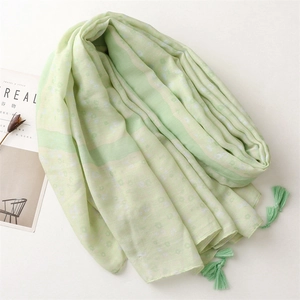 Close-up of mint green floral scarf with soft tassels and lightweight cotton linen texture