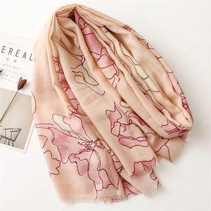 Beige floral scarf with red blossoms and fringe trim laid flat on a clean white background