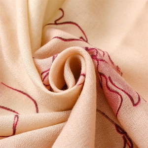 Macro shot of soft knit cream shawl with vintage red floral patterns and spiral texture