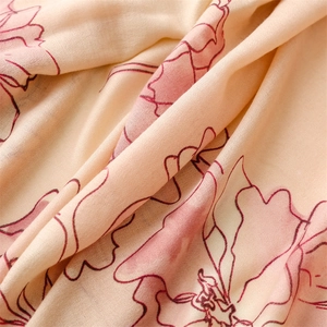 Macro shot of soft floral print fabric with pink blossoms on beige scarf texture