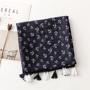 Détail d'une écharpe bleu marine à motifs d'ancres avec pompons sur fond blanc