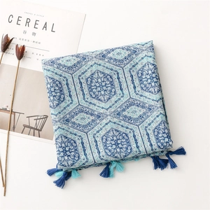 Detail of blue geometric print scarf with bohemian tassel edges on a minimal white surface