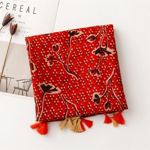 Detail of red floral cotton scarf with fringe and vintage pattern on a clean background