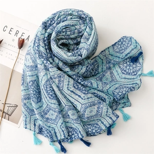 Detailed view of blue ethnic geometric print scarf with decorative tassels on white background
