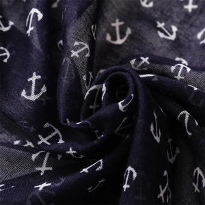 Détail macro d'une écharpe bleu marine avec motifs ancres blanches et texture tissée
