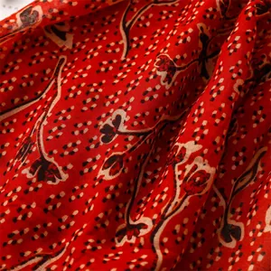Close-up of red cotton linen scarf with black floral print and polka dot texture