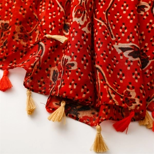 Close-up of ethnic red floral scarf with detailed bicolor tassels and soft cotton texture