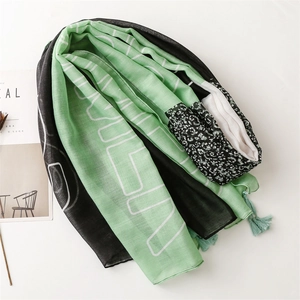 Écharpe vert menthe et noire à motifs géométriques et pompons à franges