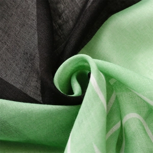 Gros plan d'une écharpe légère vert et noir aspect lin avec motifs de lignes fluides