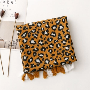 Détail d'une écharpe léopard jaune avec franges à côté d'un magazine de mode