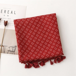 Détail d'une écharpe rouge en coton et lin avec motifs d'étoiles et bords à franges