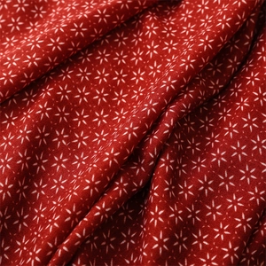 Détail macro d'une écharpe ethnique rouge avec motifs d'étoiles et texture du tissu