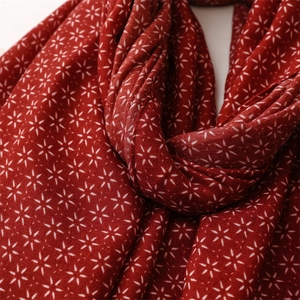 Gros plan détaillé de l'écharpe rouge aspect lin avec motifs d'étoiles hexagrammes