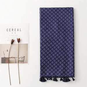 Détail d'une écharpe bohème en coton bleu marine avec motifs d'étoiles et de pompons