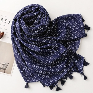 Détail d'une écharpe bohème bleu marine avec motifs floraux blancs et pompons