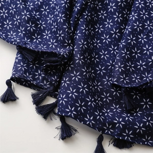 Détail d'une écharpe ethnique bleu marine avec motifs d'étoiles et pompons à franges