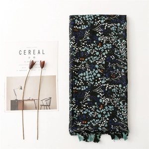 Floral cotton linen scarf with blue flower print and tassels on a minimalist background