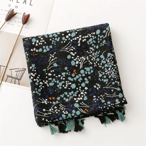 Close-up of vintage cotton-linen scarf featuring blue floral prints and tassel fringe detail