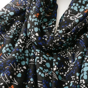 Close-up of lightweight floral scarf with navy print and delicate tassel details