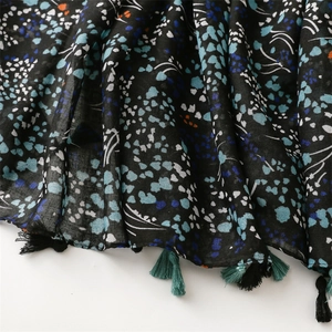 Close-up of floral print cotton linen scarf featuring dark tassels and fabric texture