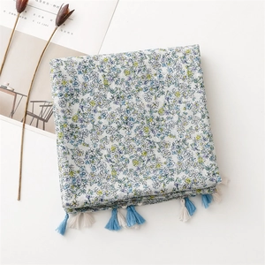 Detail of floral linen-feel scarf showing blue flower patterns and long tassel edges