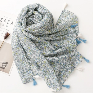 Detail of floral linen scarf showing blue flower patterns and fringed tassel edges