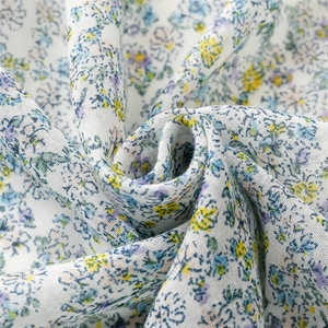 Detailed close-up of light blue floral cotton-linen scarf with elegant fringed edges