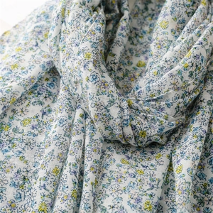 Close-up of semi-transparent floral scarf fabric showing soft drape and light blue flower print