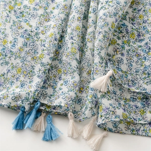 Close-up of lightweight floral cotton linen scarf with soft blue tassels and fine texture