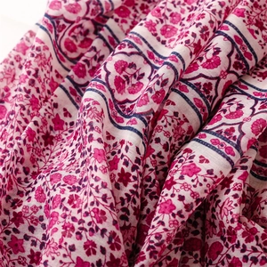 Close-up of floral print cotton-linen scarf fabric texture in magenta and red tones
