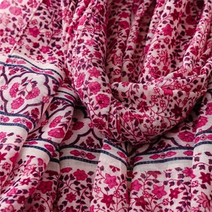 Close-up of rose red floral fabric with bohemian print and soft fringe details