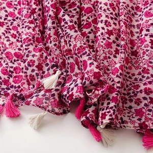 Detail of rose pink floral pattern and soft fringe tassels on a cotton-linen feel scarf