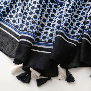 Detail of navy blue beach shawl with white polka dots, stripes, and tassel fringe