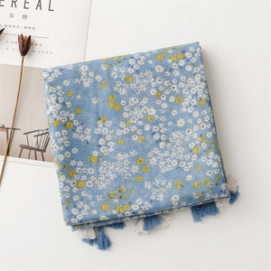 Detailed view of light blue floral scarf with elegant tassels and breathable fabric texture