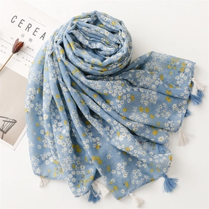 Close-up of light blue floral scarf with daisy patterns and white fringe tassels