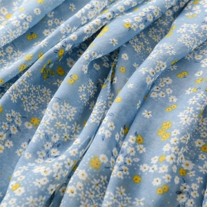 Close-up of light blue floral cotton scarf fabric with soft drapes and tassels