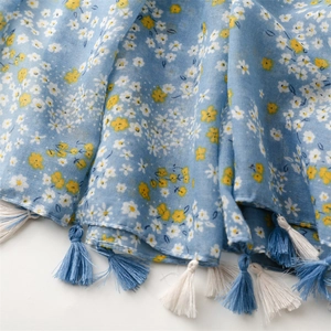 Close-up of light blue floral scarf featuring long tassels and soft linen texture