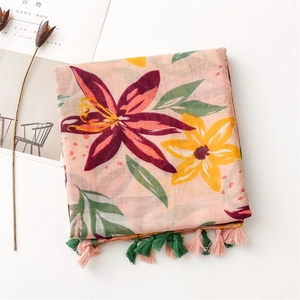 Close-up of tropical lily floral print on pink scarf with soft cotton-linen texture tassels