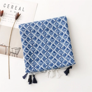 Detailed view of blue and white floral cotton scarf with tassel trim edges and texture