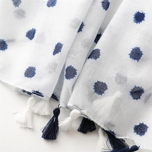 Detail of blue ink dot print on white linen fabric with bicolor fringe tassels