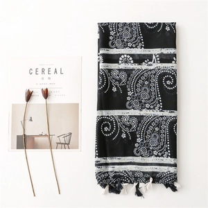 Vintage black and white paisley scarf with tassels laid flat with magazine and flowers