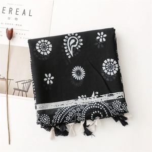 Detailed view of paisley and daisy print linen shawl with decorative black and white tassels
