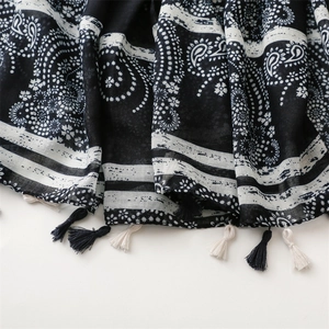 Macro view of black and white paisley pattern scarf with elegant tassel trim detailing