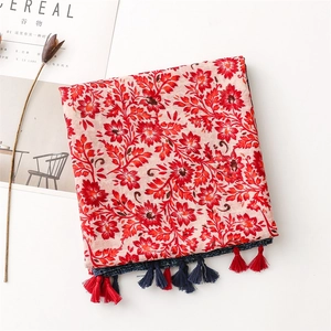 Detailed macro view of vintage red floral pattern and bicolor tassels on a cotton linen shawl
