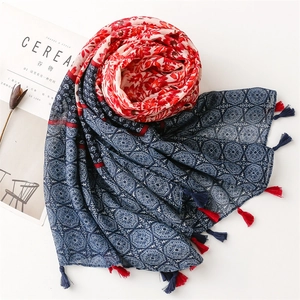 Detail of ethnic floral and geometric print scarf with decorative red and blue tassels